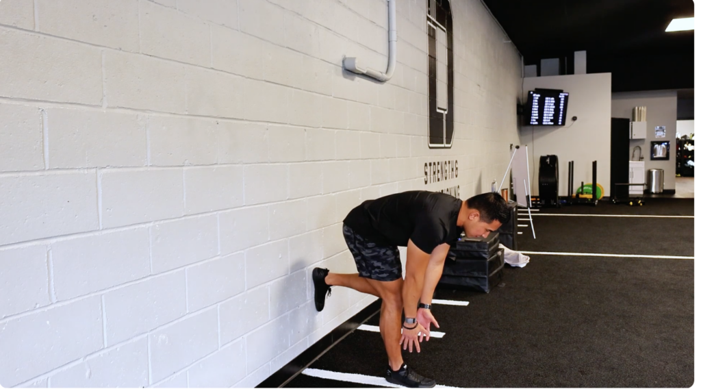 hamstring stretch for athletes using wall support